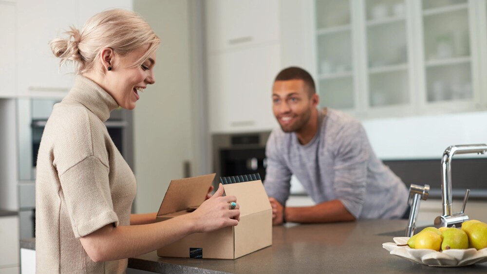 Happy couple opening a package in a domestic kitchen setting