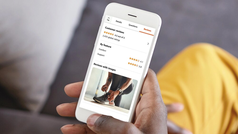 Closeup on person's hands holding smartphone device and reading customer reviews and ratings for athletic sneakers