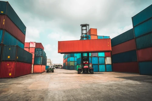 Forklift truck with shipping containers in an open-air industrial setting