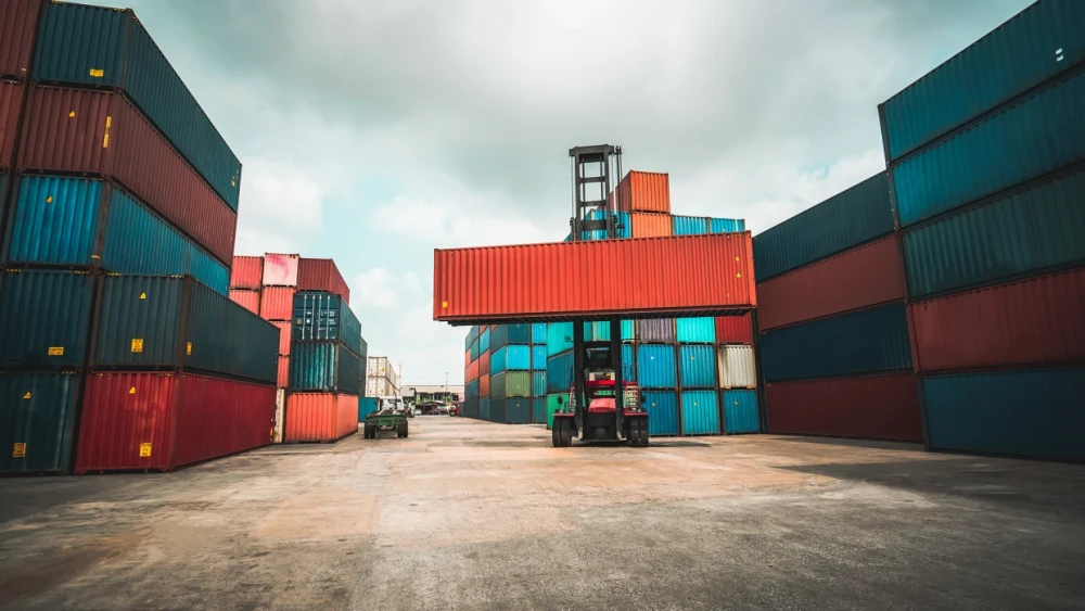 Forklift truck with shipping containers in an open-air industrial setting