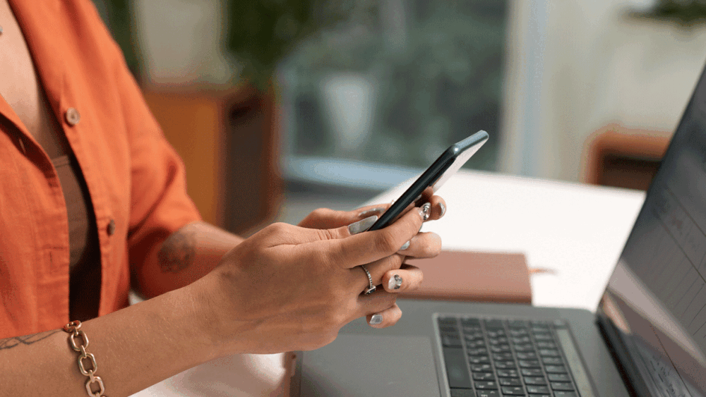 person checking phone while on laptop