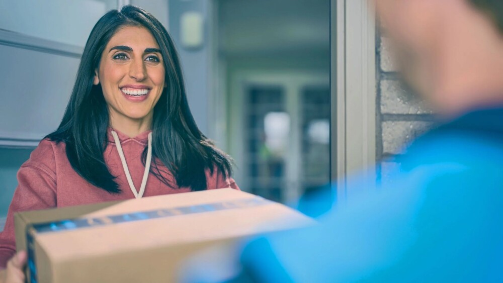 Smiling customer at doorstep receiving package delivery